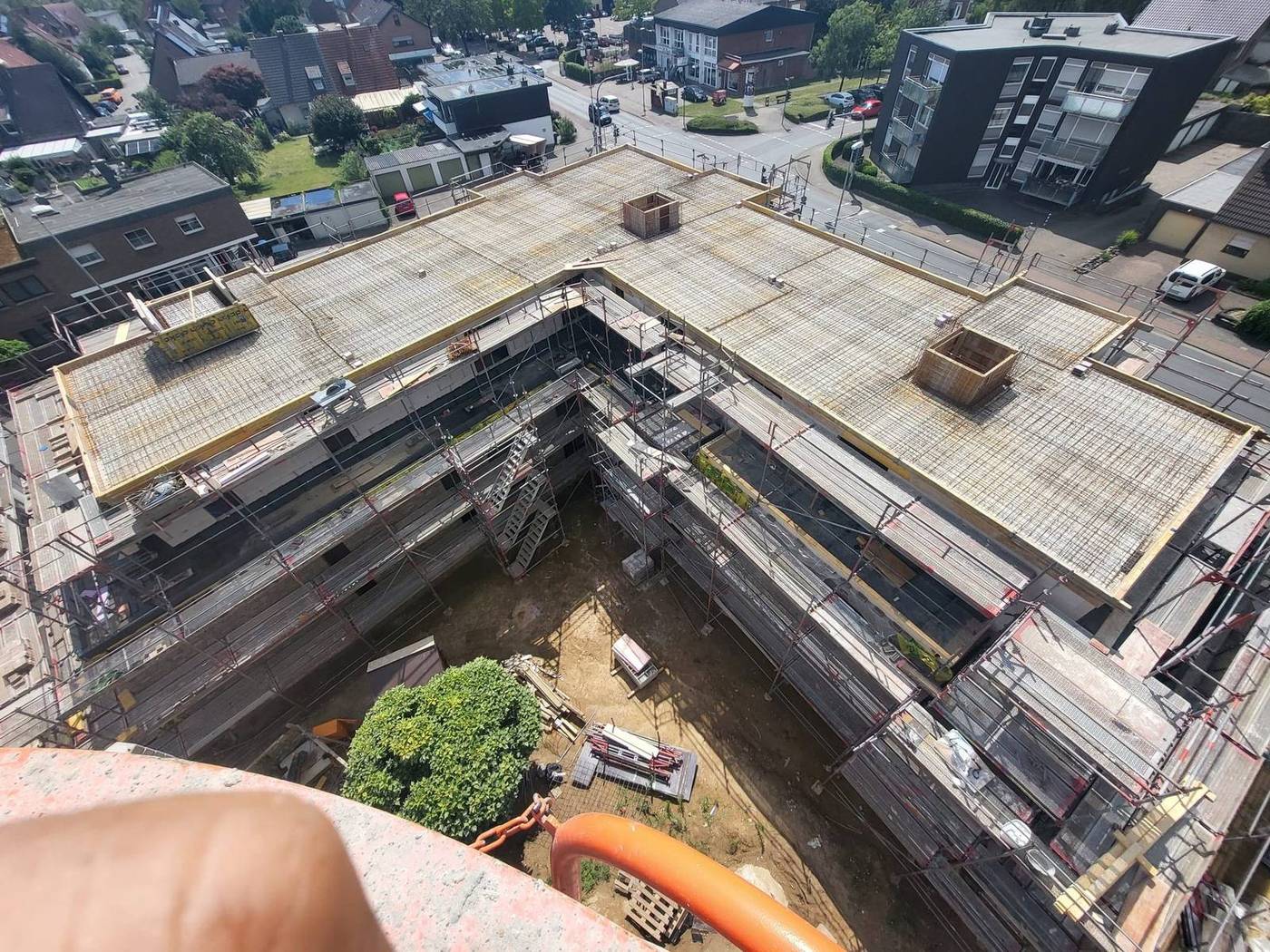 Luftaufnahme einer Geschossdecke mit verlegter Bewehrung und Schalungsrand, umgeben von Gerüsten