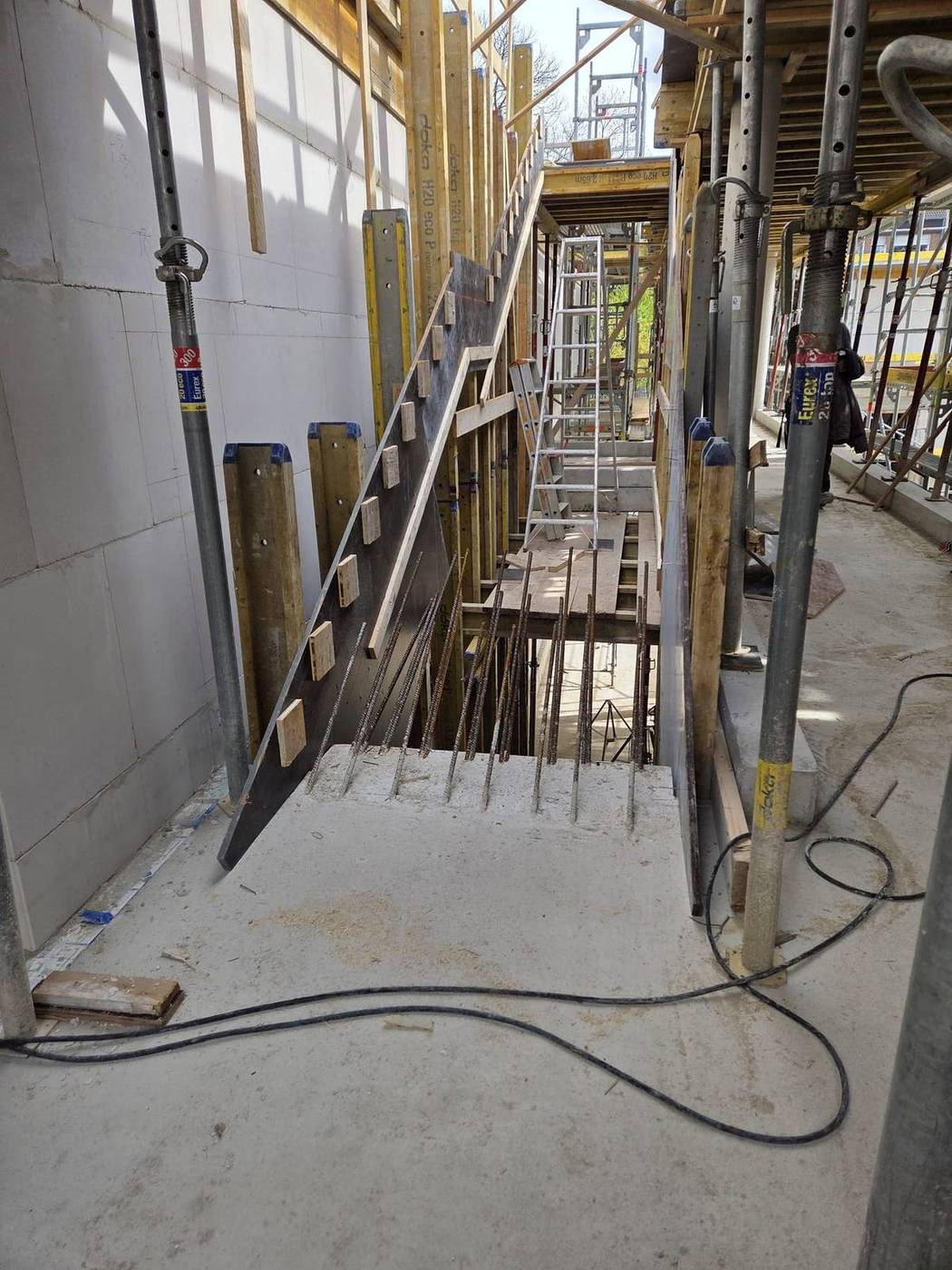 Schalung einer Treppe zwischen Wand und Stützen mit herausragender Bewehrung