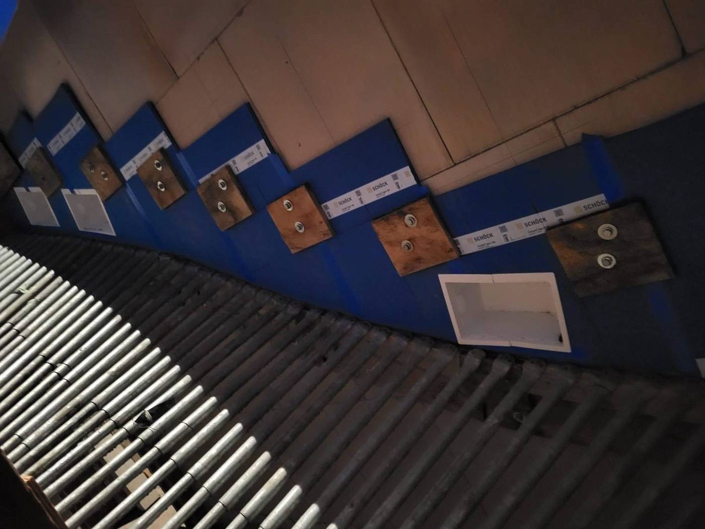 Blaue Anschlusselemente an der Wand über verlegten Stahlstäben