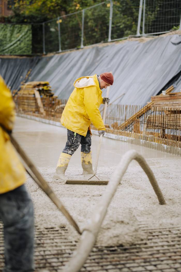 Bauarbeiter mit Rakel im frischen Beton